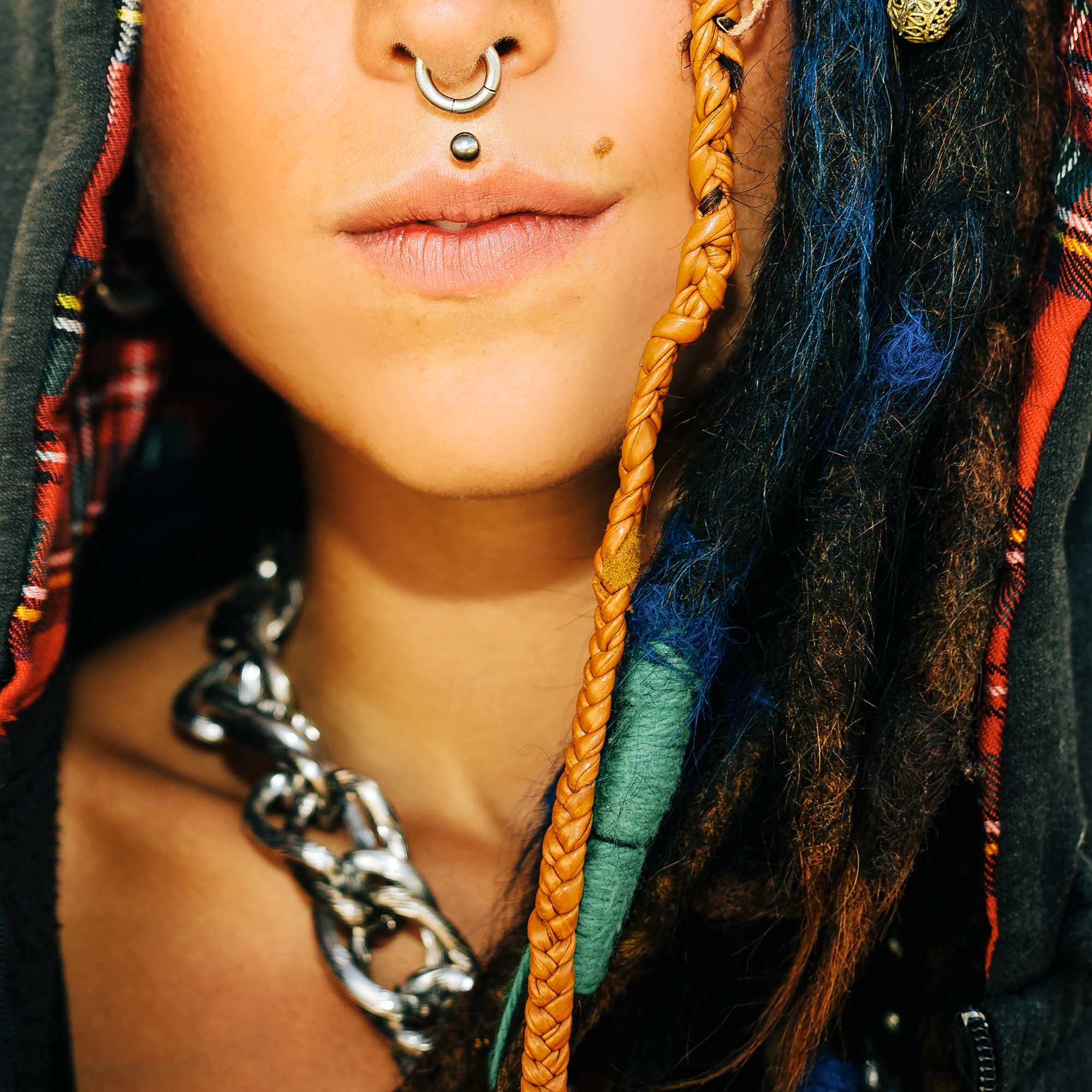 Close-up portrait. Girl with dreadlocks and piercings. Fashionable accessories. Street style