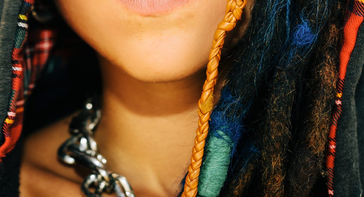 Close-up portrait. Girl with dreadlocks and piercings. Fashionable accessories. Street style